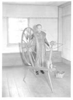 SA0123 - An older unidentified Shaker woman using a spinning wheel near window.